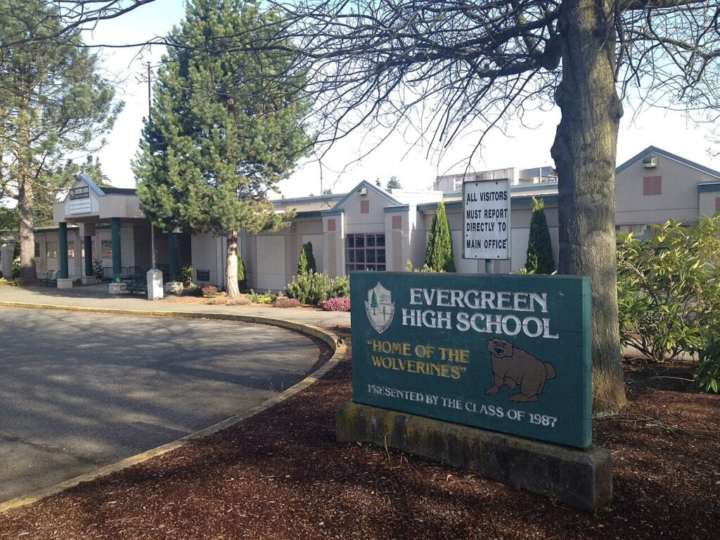 Evergreen High School entrance with sign that says visitors must check in at front office.