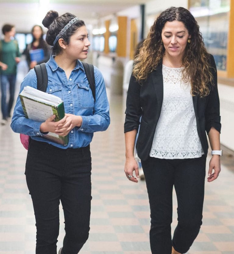 Student and adult walking in school hallway