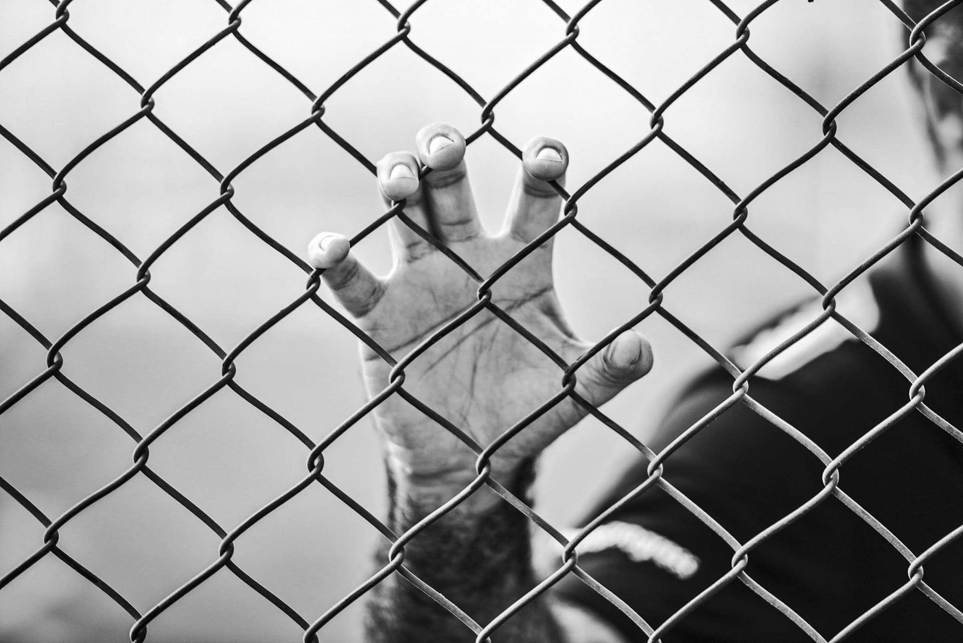man standing by chain link fence
