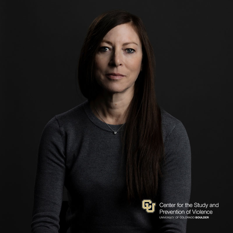 Headshot of a white woman with long dark hair wearing a dark grey sweater.