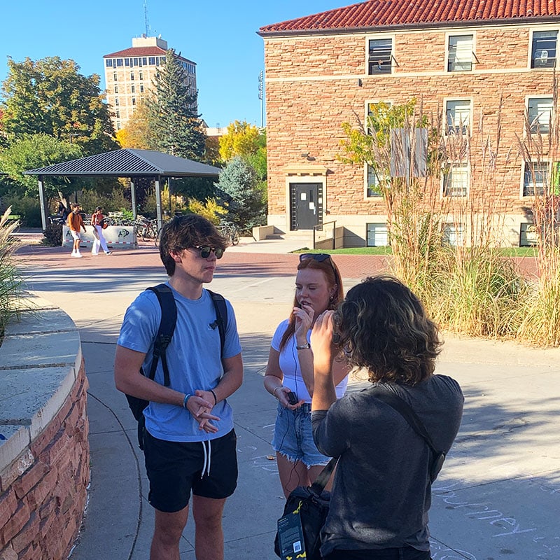 Three students speaking outside on campus.