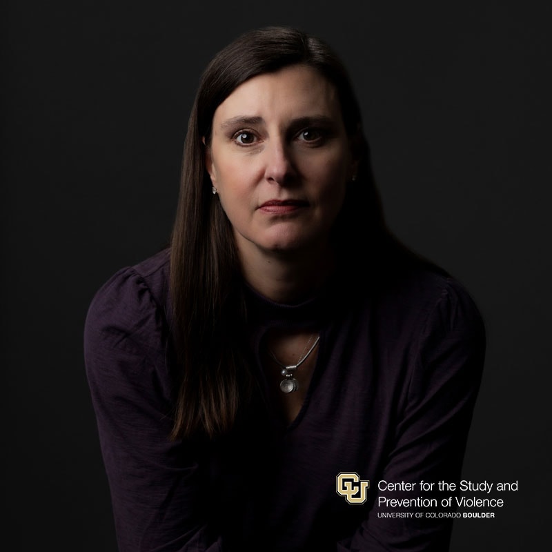 Headshot of a white woman with long dark brown hair wearing a dark purple blouse.