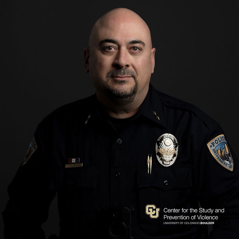 Headshot of a white bald man with facial hair wearing a police uniform.