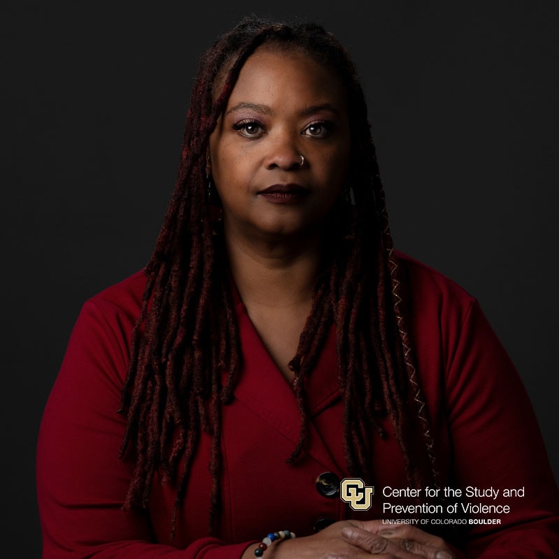 Headshot of a black woman with long brown hair wearing a read top.
